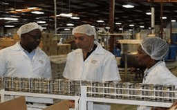 Factory workers in white coats working on production line