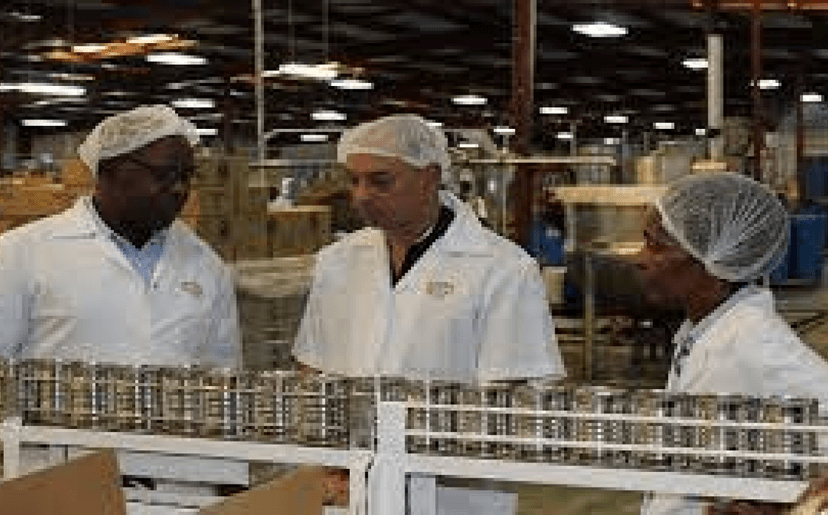 Factory workers in white coats working on production line