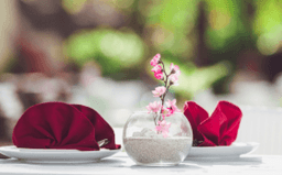 Hotel table setting with red napkin and small flower vase